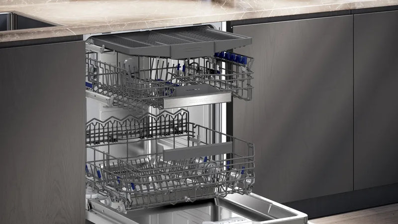 Open dishwasher with silver interior and racks in a kitchen setting